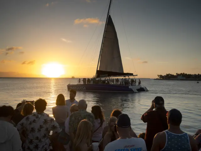 Catamaran packed with passengers sailing past the sunset crowd at Mallory Square