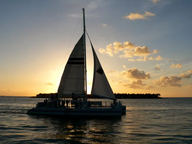 Sailing catamaran full of passengers heading out at sunset off Key West